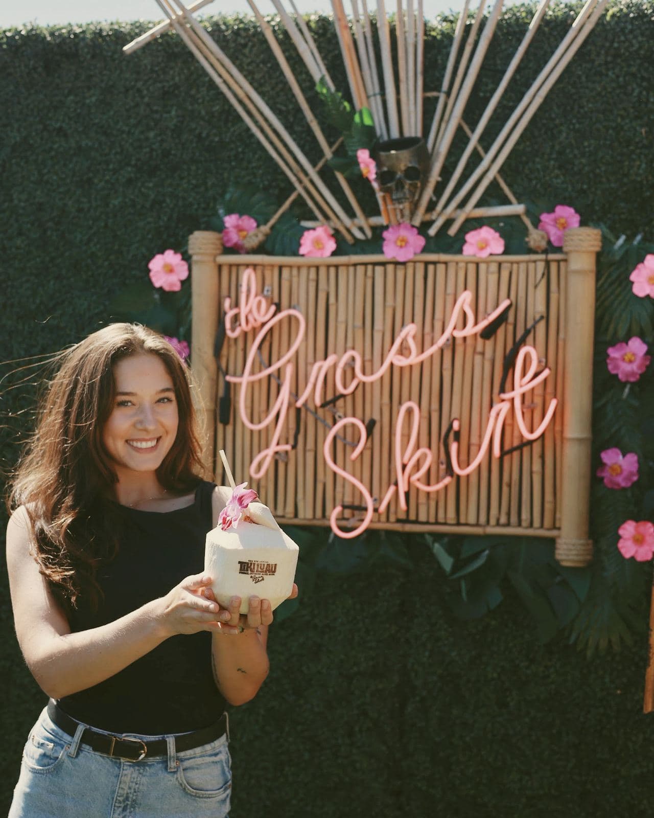 Guest with a stamped coconut under the Grass Skirt neon sign