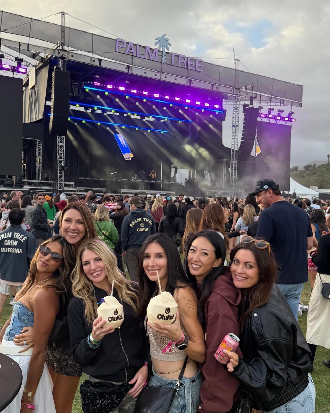 Festival guests holding OluKai coconuts in front of the Palm Tree main stage