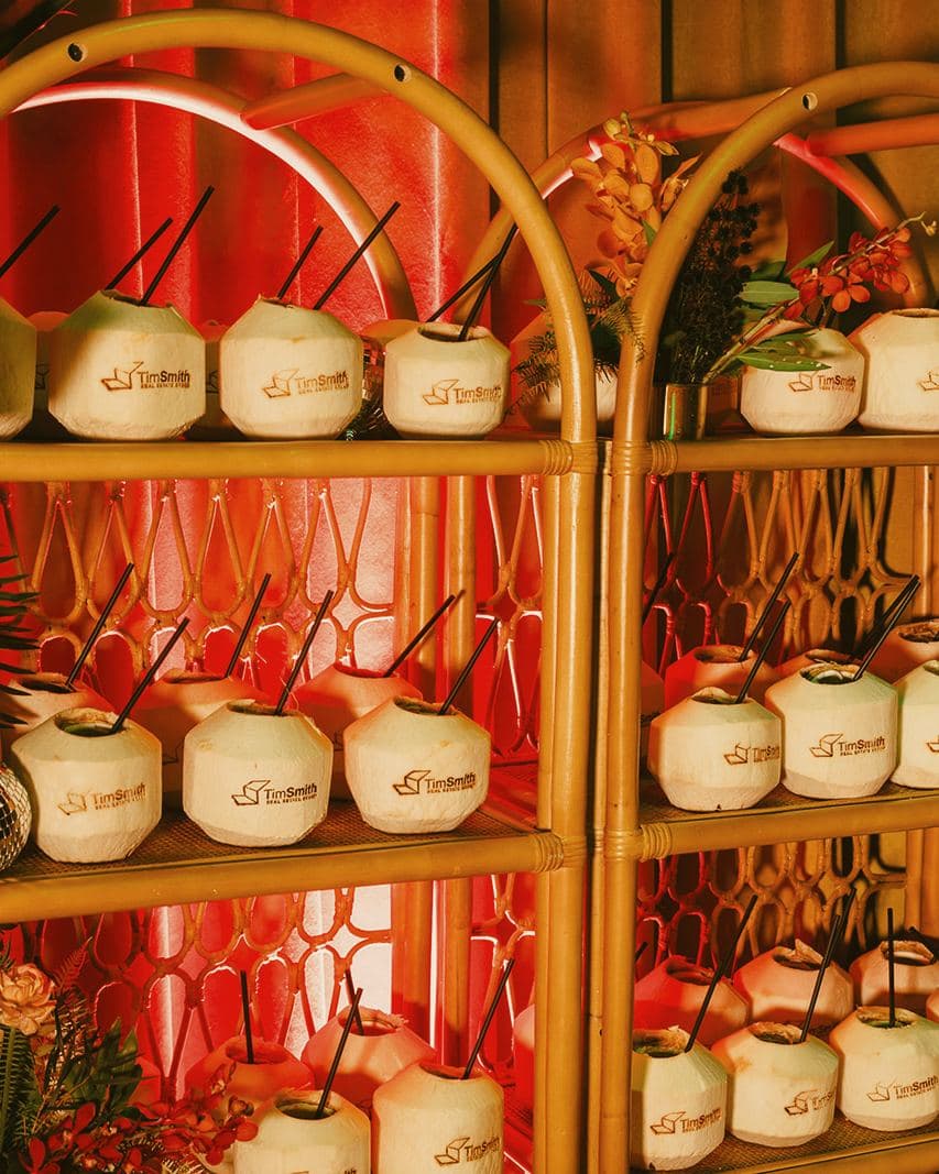 Shelves of stamped coconuts with black straws at a holiday party at the Pendry