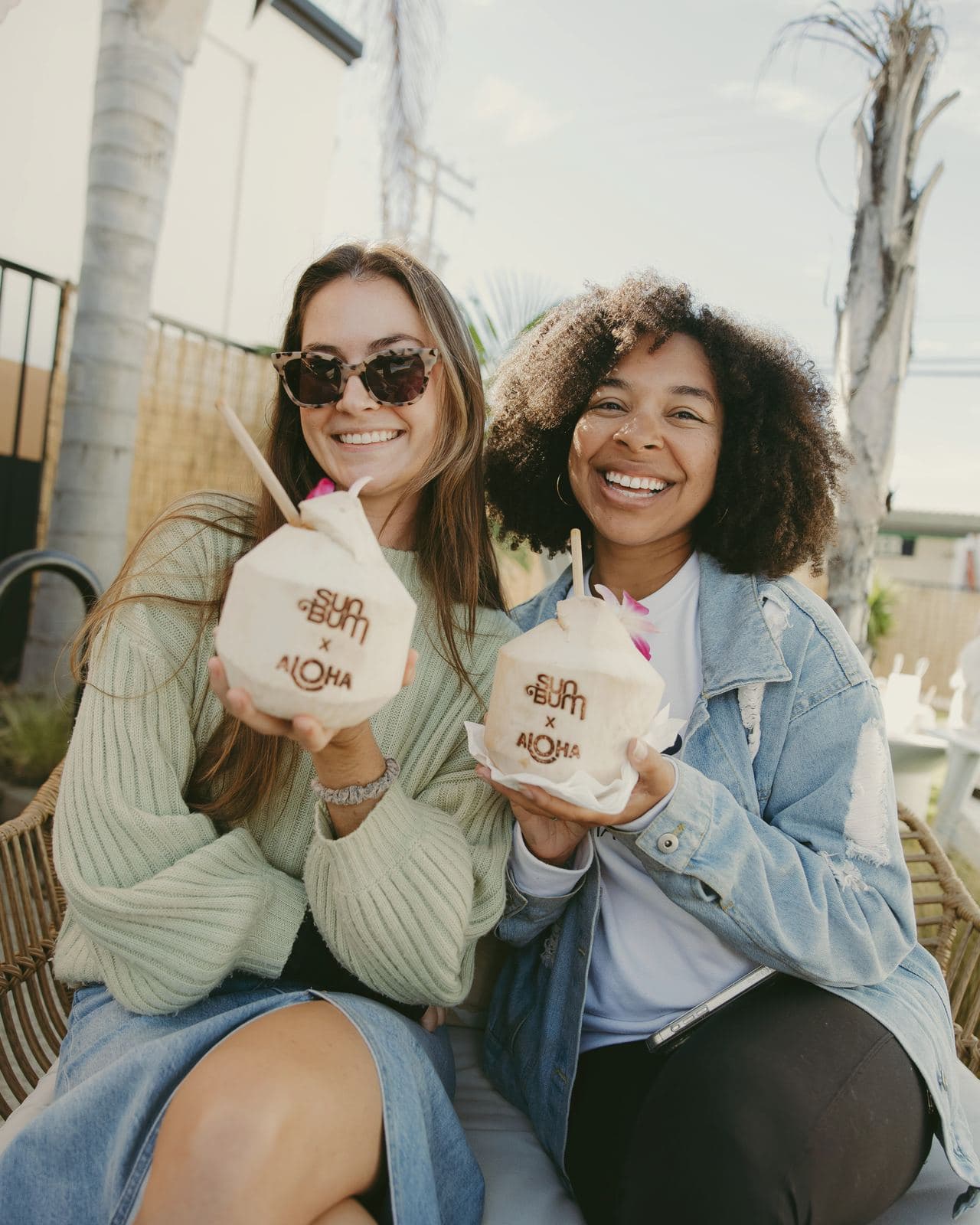 Two guests holding Sun Bum x Aloha coconuts