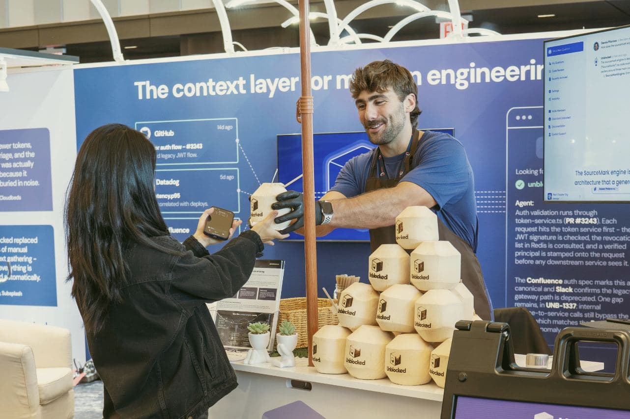 Specialist handing an attendee an Unblocked-stamped coconut at the Unblocked booth