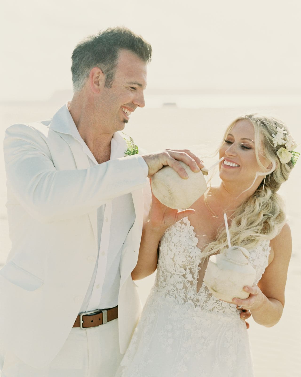 Bride and groom on the beach with stamped coconuts