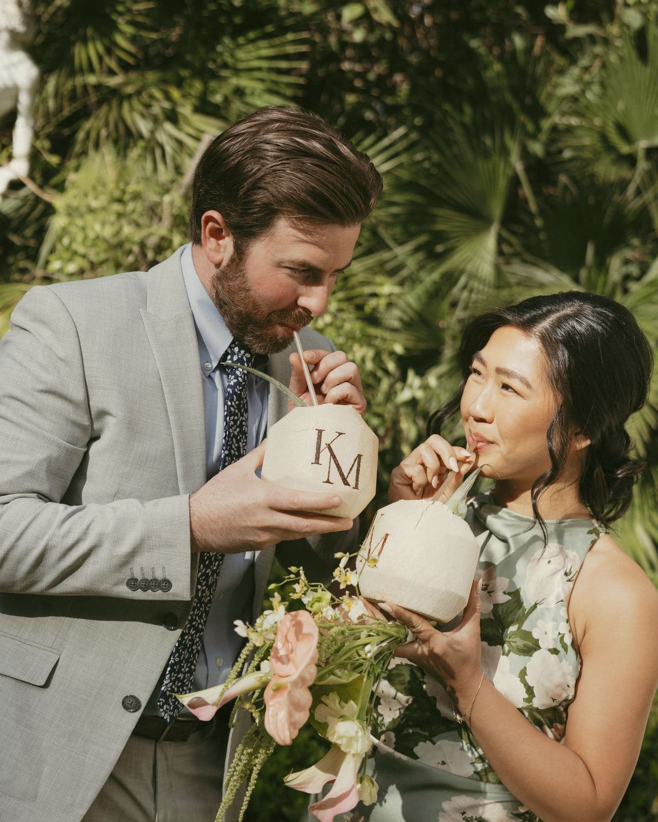 Couple sipping from KM-monogrammed coconuts in the garden